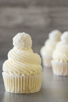 two cupcakes with white frosting on top and the words raffaello cupcakes above them