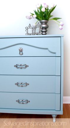 a blue dresser with flowers on top of it