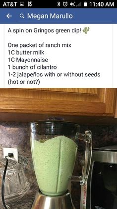 a blender filled with green liquid sitting on top of a counter next to a microwave