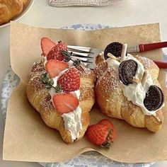 two croissants with strawberries and cream on them