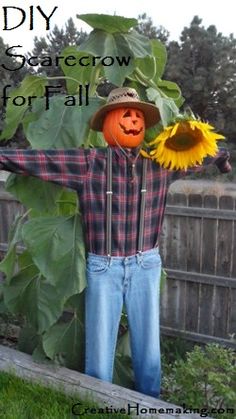 a scarecrow with sunflowers on his head and arms in front of a fence