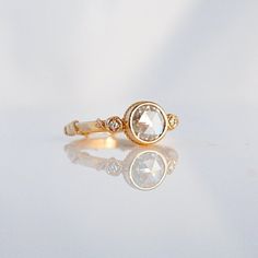 a diamond ring sitting on top of a white table next to a reflection in the floor