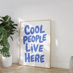 a blue and white sign sitting on top of a wooden floor next to a potted plant