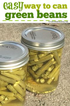 two jars filled with green beans sitting on the ground