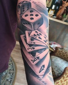 a person with a tattoo on their arm holding some dice