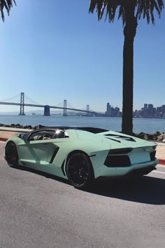 a green sports car parked on the side of the road in front of a bridge