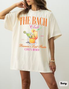 a woman wearing a white t - shirt that says the beach club with a cocktail on it