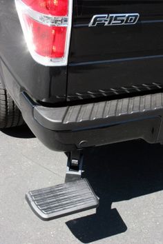 the rear end of a gray truck with a metal step