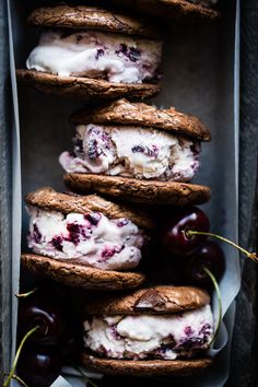 cookies and ice cream are stacked on top of each other with cherries in the background