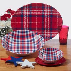 red, white and blue plaid dinnerware set on wooden table with flowers in vase