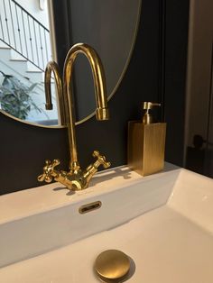 a bathroom sink with gold faucet and soap dispenser