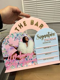 a pink and gold sign that says the bar with a woman's photo on it