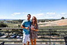 a man and woman standing next to each other in front of a balcony with a view