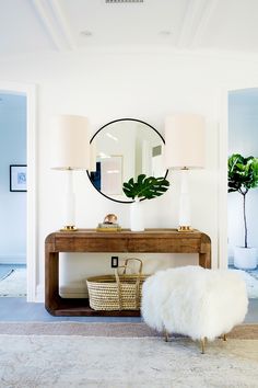 a living room with a table and mirror on the wall