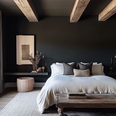 a bedroom with black walls, white bedding and wooden beams on the ceiling is shown