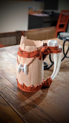 a wooden table topped with a coffee mug covered in brown and white paper mache