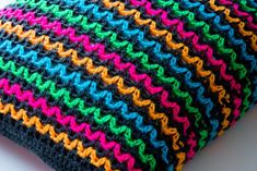 a multicolored crocheted pillow sitting on top of a white table