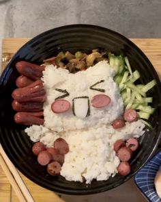 a plate with rice, sausages and other food items in the shape of a cat