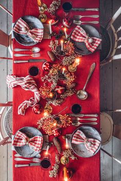 the table is set with silverware and red napkins on it, along with candles