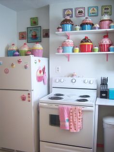 a white stove top oven sitting inside of a kitchen next to a wall with cupcakes on it