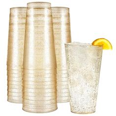 a tall glass with an orange slice in it next to several smaller glasses that are stacked on top of each other