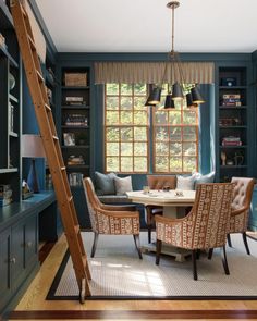 a dining room with blue walls and wooden flooring next to a ladder leading up to the window