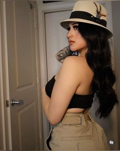 a woman wearing a hat and scarf standing next to a door with her hand on her shoulder