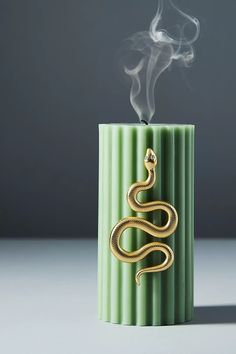 a green candle with a gold snake on it