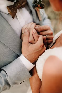 a bride and groom holding hands while standing next to each other