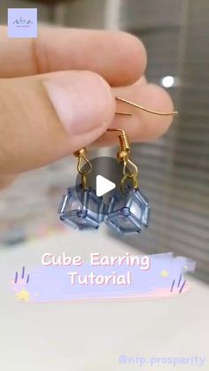 a person is holding up some earrings with words on it that read cube earing