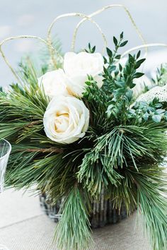 white flowers and greenery in a vase on a table