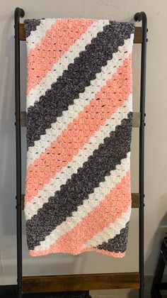 a crocheted blanket hanging on a rack in a room next to a wall