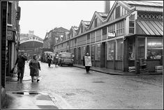 an old black and white photo of people walking down the street