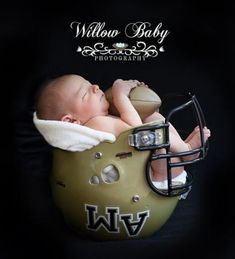 a baby laying on top of a football helmet