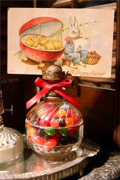 a glass jar filled with gummy bears on top of a metal table next to a card