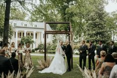 a bride and groom standing at the end of their wedding ceremony in front of a large white house