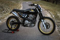 a black and yellow motorcycle parked on the side of a road next to a field