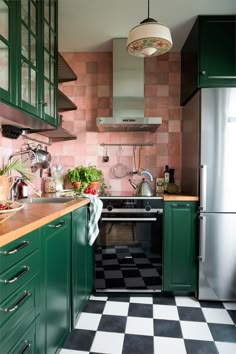 a kitchen with green cabinets and black and white checkerboard flooring on the walls