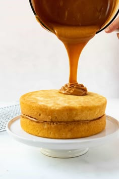 someone pouring caramel sauce on top of a cake