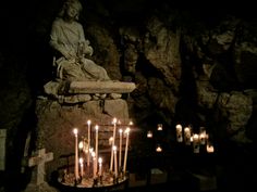 many candles are lit in front of a statue