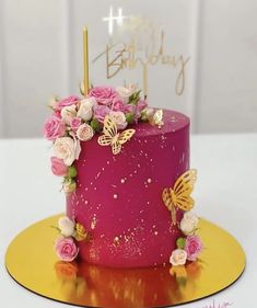 a pink birthday cake with flowers and butterflies on top, sitting on a yellow plate