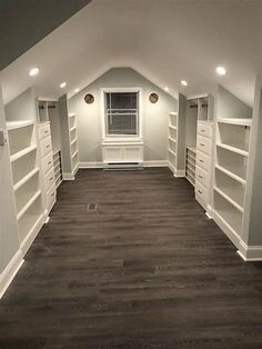 an empty room with white shelving in the corner and dark wood flooring on the other side