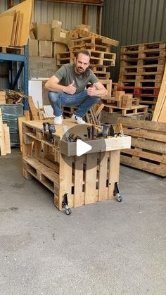 a man sitting on top of a wooden table surrounded by pallet boxes and crates