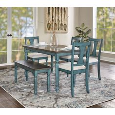 a dining room table with chairs and a bench in front of the window on an area rug