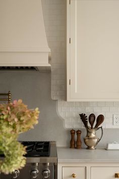 a kitchen with white cabinets and wooden utensils on the counter top, next to an oven