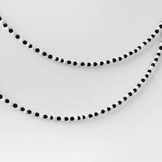 two black and white beads are hanging from the side of a necklace on a string