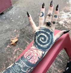 a woman's hand with tattoos and rings on it