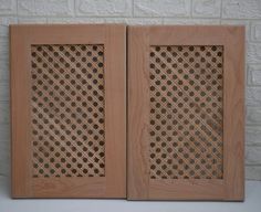 two wooden panels with holes in them on a white table next to a brick wall