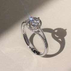 a diamond ring on a white surface with the shadow from it's back side