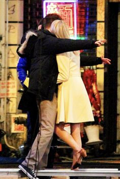 a man and woman hugging in front of a store window with their arms around each other